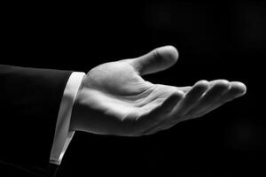 Elegant hand gesture in a formal setting, showcasing invitation or offering in darkness photo