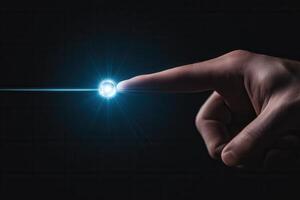 A human finger reaching out to touch a glowing orb of light against a dark background photo