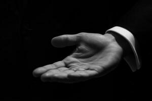 Elegant hand presenting a wedding ring, symbolizing love and commitment in a dark setting photo