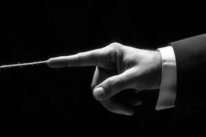 Close-up of a man's hand gently touching a thin string, creating a dramatic contrast in a dark setting photo
