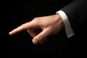 Elegant hand gesture in a formal suit pointing towards an unseen object in darkness photo