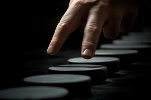 A close-up of a hand gently touching a series of circular objects in a dark setting photo