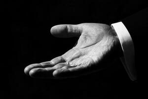 Elegant open hand gesture in black and white against a dark background, suggesting invitation photo