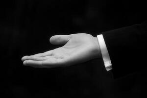 A formal hand gesture inviting assistance, set against a blurred dark background photo