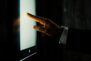 Elegant hand reaching towards a touchscreen interface in a dimly lit modern environment photo