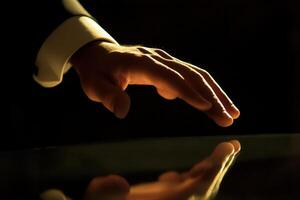 Elegant hand reaching out to touch a reflective surface in a dimly lit environment photo