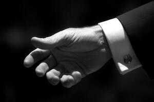 Elegant hand gesture in formal attire, showcasing a welcoming invitation in soft lighting photo