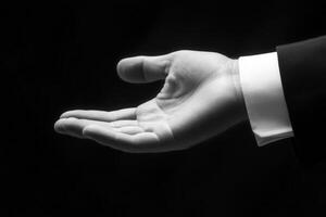 Elegant hand gesture in a business suit, showcasing an open palm against a dark backdrop photo