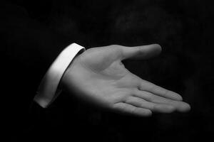 Elegant open hand gesture against a dark background, suggesting invitation or offering photo