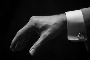 Elegant hand gesture in formal attire, showcasing refined style against a dark backdrop photo