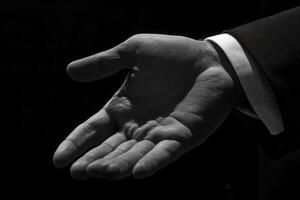 Elegant outstretched hand in a formal suit against a dark background inviting connection photo