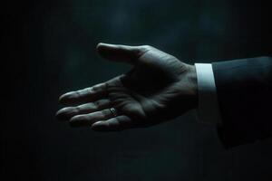 A businessman's outstretched hand reaching out in a dimly lit environment, symbolizing opportunity photo