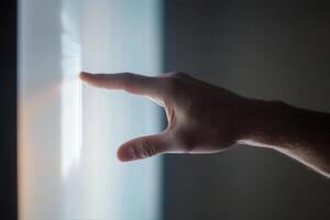 A hand reaching towards a glowing screen, exploring digital interaction in a modern setting photo