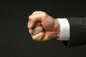 A determined businessman clenches his fist, symbolizing strength and resolve against a dark backdrop photo