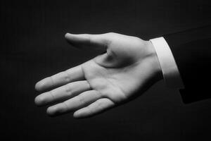 Elegant black and white image of an outstretched hand in a formal suit inviting connection photo