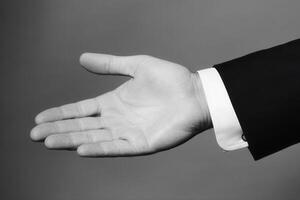 Elegant hand gesture in formal attire inviting collaboration against a soft gray backdrop photo