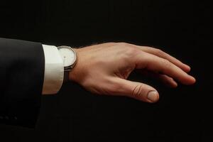 Elegant hand of a businessman in a suit reaching out against a dark background photo