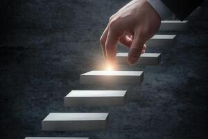 A hand reaching for a glowing step on a staircase, symbolizing progress and ambition photo