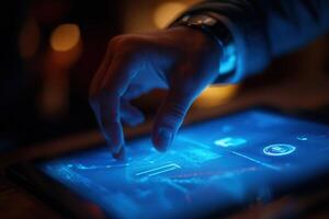A close-up of a hand interacting with a glowing tablet screen displaying data analytics in a dimly lit setting photo