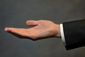 Elegant open hand gesture in a formal suit against a soft-focus background, symbolizing invitation photo