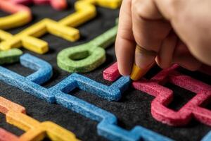 A close-up of a hand placing colorful puzzle pieces on a black surface, engaging in a creative activity photo