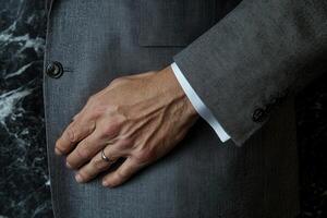 Elegant close-up of a man's hand adjusting a suit jacket against a marble background photo