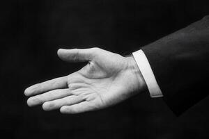 Elegant black and white image of an outstretched hand in a business suit, inviting collaboration photo
