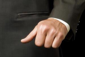 Close-up of a well-groomed man's hand in a suit, poised confidently against a dark background photo