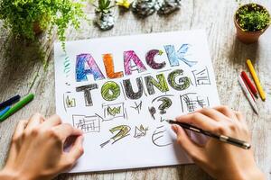 Creative hands drawing colorful illustrations and text on paper with art supplies nearby photo