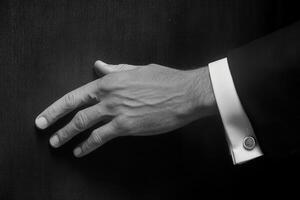 Elegant hand in a formal cufflink reaching towards a textured surface, showcasing sophistication photo