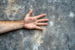 A human hand reaching out against a textured stone wall, symbolizing connection and outreach photo