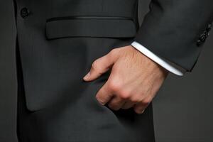 Elegant businessman adjusting suit pocket in a professional setting with dark background photo