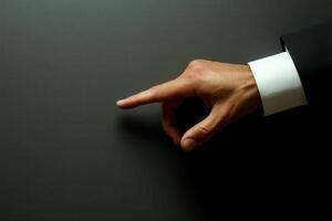 Elegant hand gesture pointing towards a dark surface, suggesting direction or emphasis photo