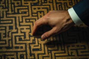 A businessman navigating a complex maze pattern on a table, symbolizing strategic decisions photo