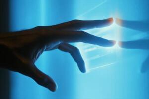 A human hand reaching towards a glowing interface, set against a blue-lit background photo