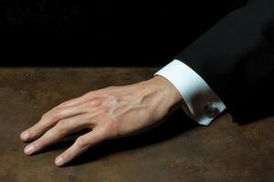 Elegant hand of a well-dressed individual resting on a textured surface, highlighting sophistication photo
