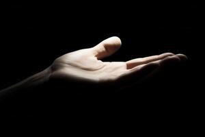 Hand reaching out against a dark background, symbolizing hope and connection photo