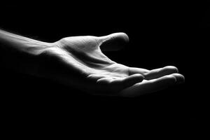 Monochrome hand reaching out against a dark background, symbolizing connection and support photo