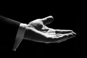 Elegant outstretched hand in formal attire against a dramatic black background photo