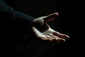 Outstretched hand in formal attire reaching out in a dimly lit environment photo