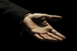 Open hand reaching out in a dramatic light setting, symbolizing invitation or help photo