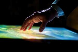 Hand interacting with a digital display showing a vibrant landscape in a dark room photo