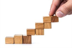 Hand arranging wooden blocks into a staircase formation on a white background photo