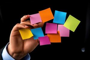Person holding colorful sticky notes in a dark setting, showcasing organization and creativity photo