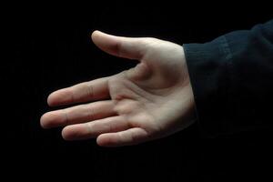 Open hand reaching out against a dark background, symbolizing connection and invitation photo