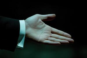 Open hand gesture in a dark setting, symbolizing invitation or greeting, with subtle shadows photo