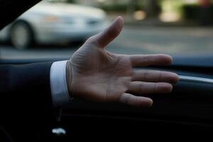 Hand reaching out of a car window, signaling for attention in a busy urban street photo