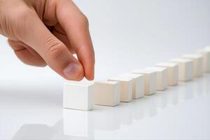 Hand placing a wooden block in a line of blocks on a reflective surface, symbolizing strategy photo