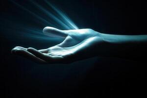 Illuminated hand reaching out in darkness, symbolizing hope and connection with soft light photo