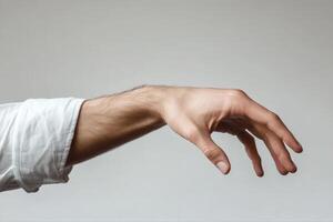 Outstretched hand of a person in a white shirt reaching forward against a neutral background photo